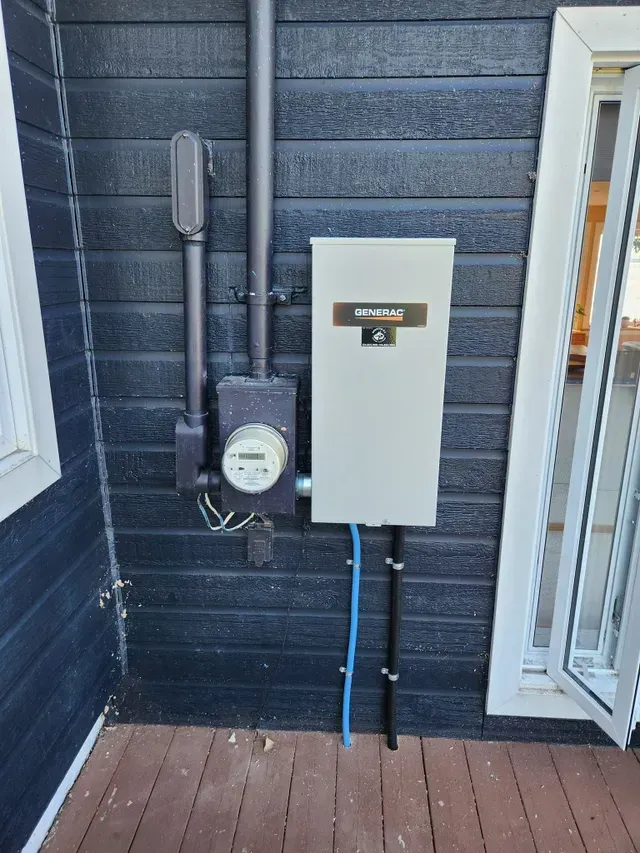A white box with a meter attached to it is on the side of a building.