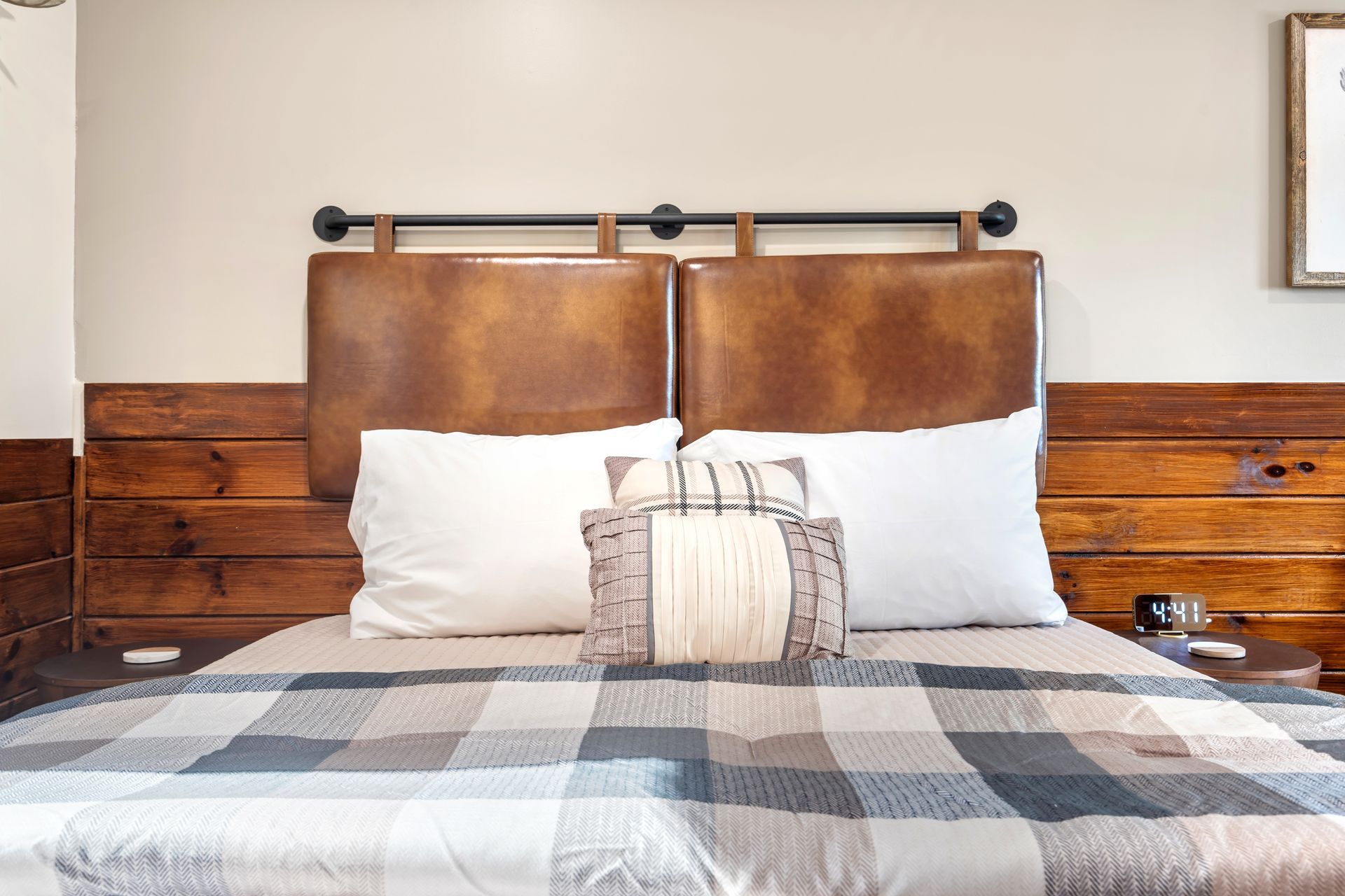Bedroom with leather headboard, wood accents, and plaid blanket on the bed.