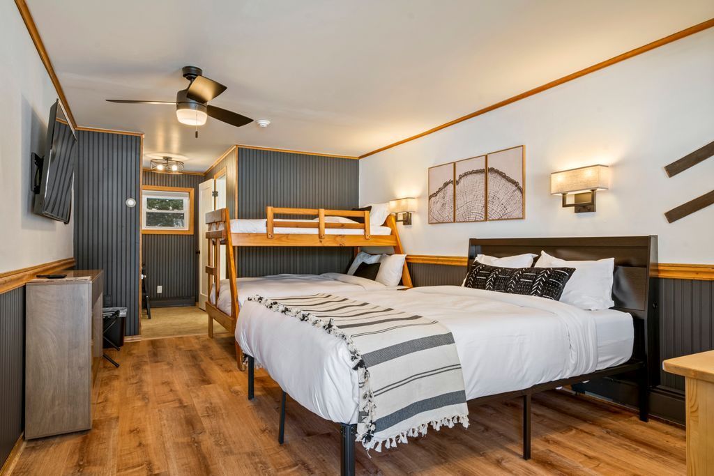 Hotel room with wood paneling, a double bed with blue sheets, and bunk beds.