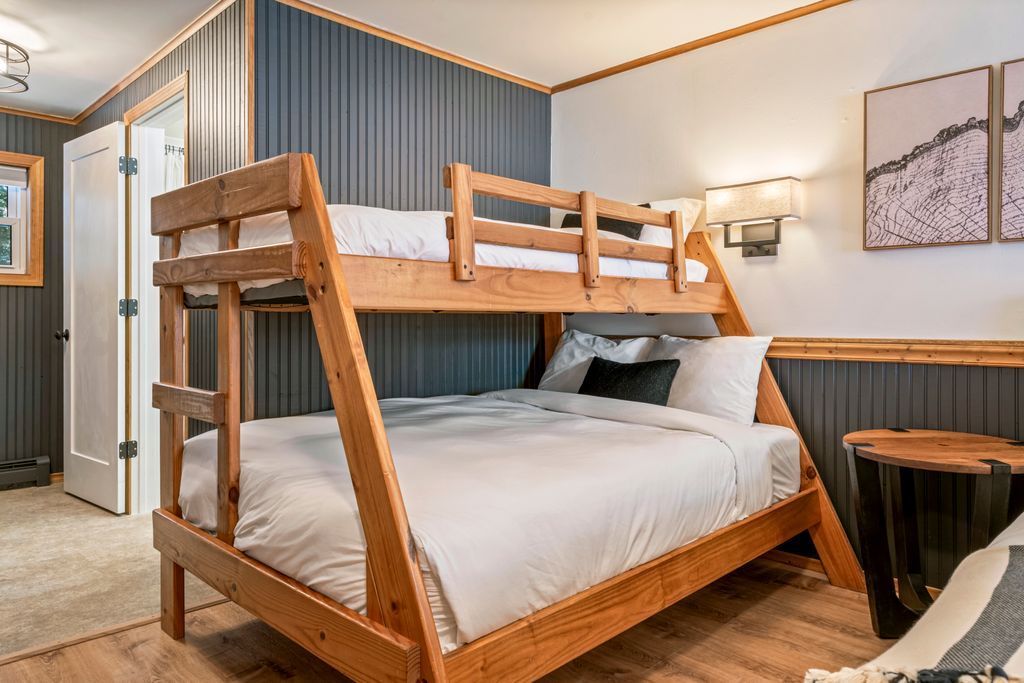 Bunk bed in a bedroom with wood paneling and decorative mountain art. Renovated room at the inn at rostay