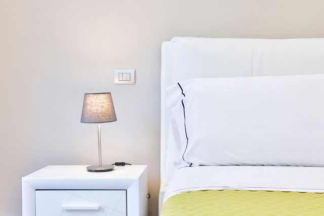 porzione di letto con materasso, comodino e lampada