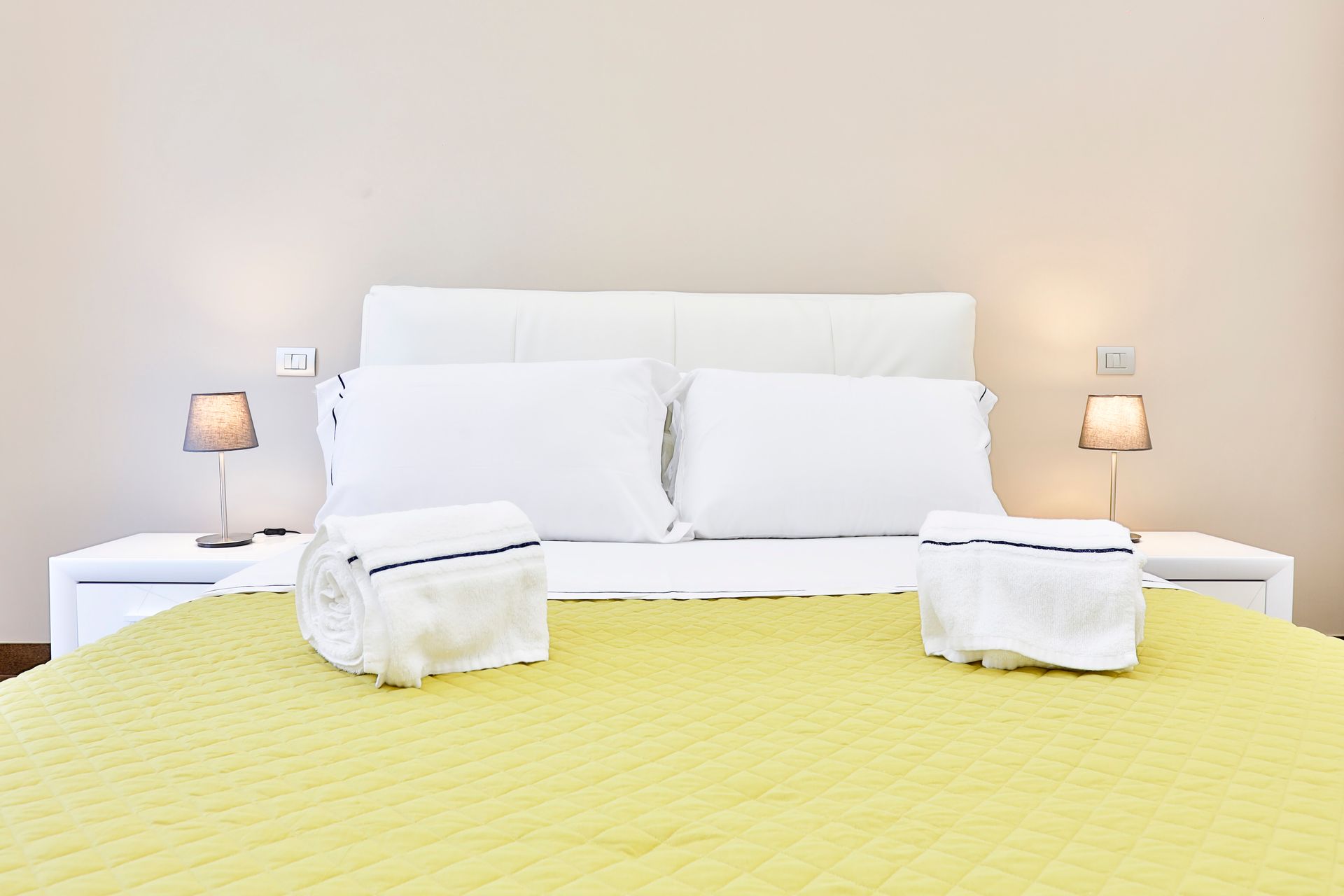 Letto con una coperta gialla e cuscini bianchi in una camera d'albergo.