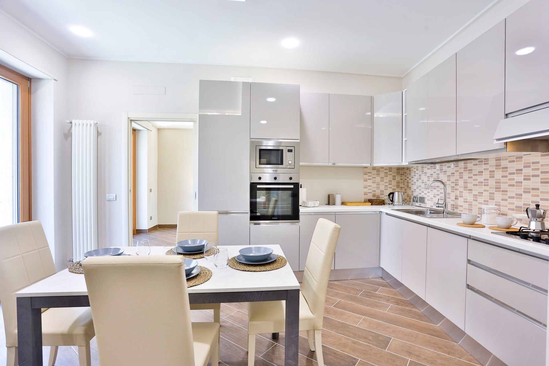 Cucina con mobili bianchi, tavolo e sedie