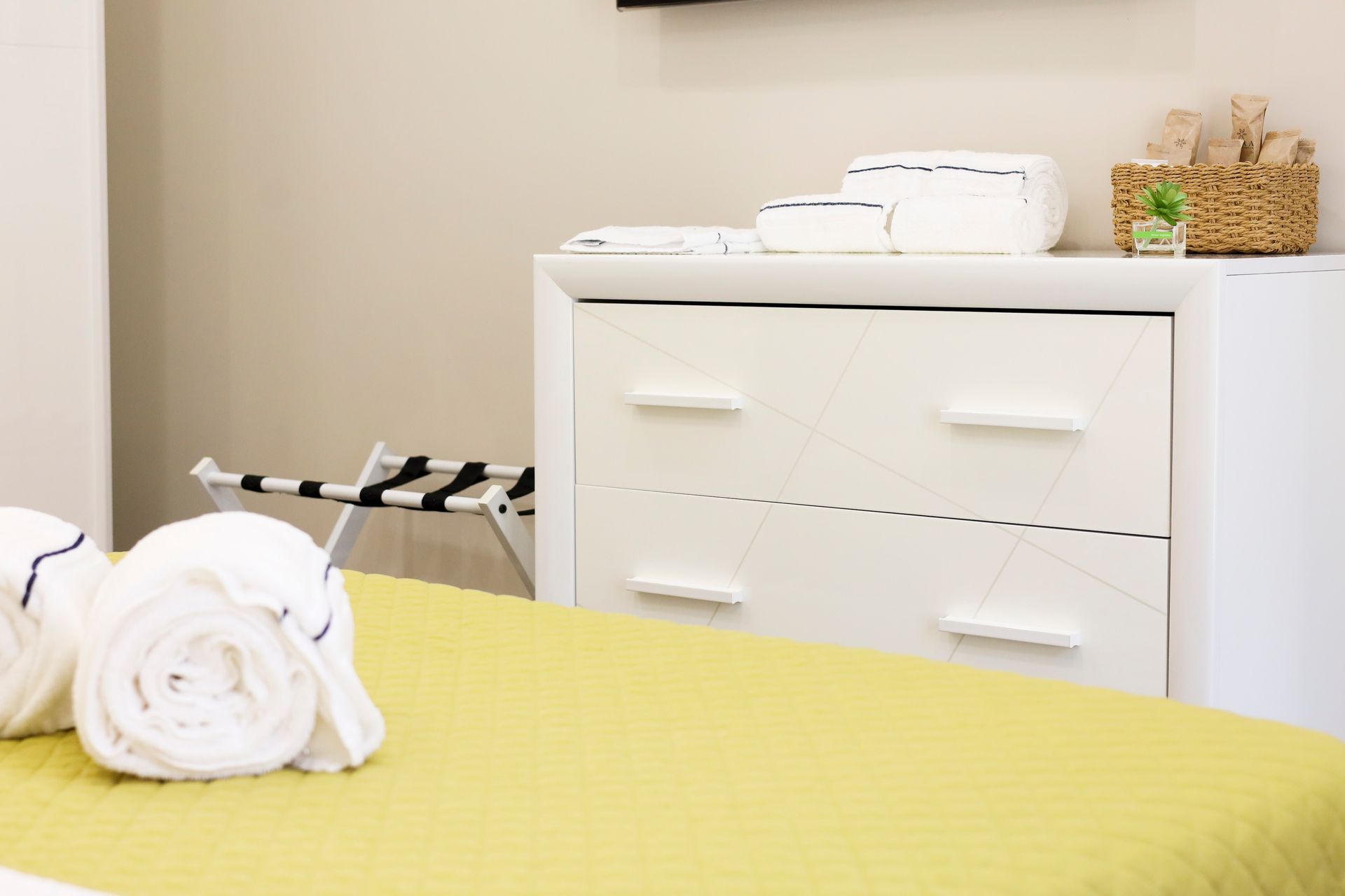 Camera da letto con un letto, una cassettiera e asciugamani sul letto.