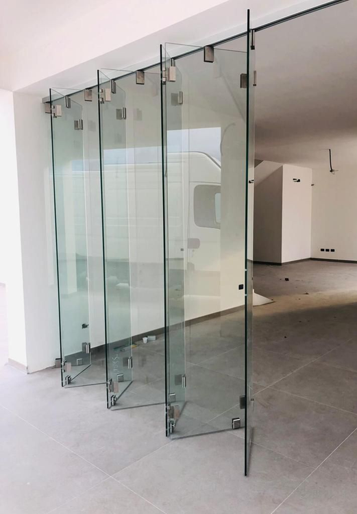 Un edificio moderno è caratterizzato da un'alta facciata continua in vetro che riflette il cielo, fiancheggiata da strutture bianche e condizionatori d'aria.