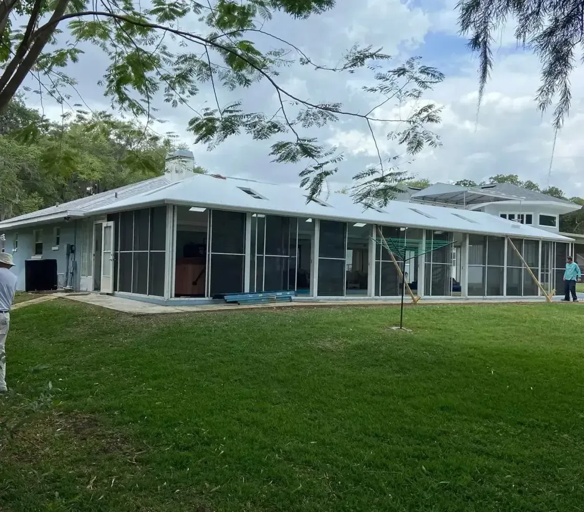 Modern house with screened porch on a grassy lawn under trees
