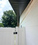 White house eaves and downspout against a bright blue sky