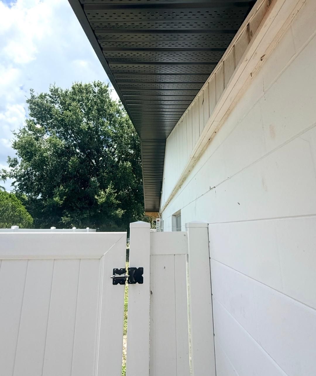 White house eaves and downspout against a bright blue sky