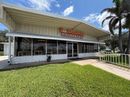 Front view of a small commercial building with an orange sign and cloudy sky