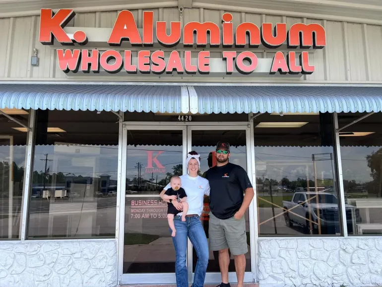 Three people standing outside K. Aluminum Wholesale To All storefront