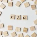 Wooden tiles spelling “FAQ” surrounded by scattered beige letter blocks on a white background