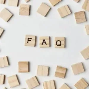 Wooden tiles spelling “FAQ” surrounded by scattered beige letter blocks on a white background