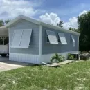 White two-story house with large windows and a striped awning over the front entrance