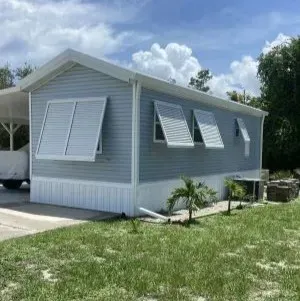 White two-story house with large windows and a striped awning over the front entrance
