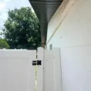 White house eaves and downspout against a bright blue sky