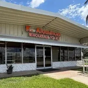 Front view of a small commercial building with an orange sign and cloudy sky