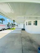 Covered concrete walkway beside a white building, with a parked truck and blue sky in the background.