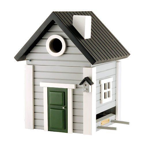 Grijs-wit houten vogelhuisje met een donker dak en een groene deur.