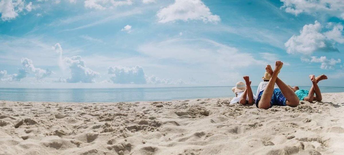 A group of people are laying on their stomachs on a beach.