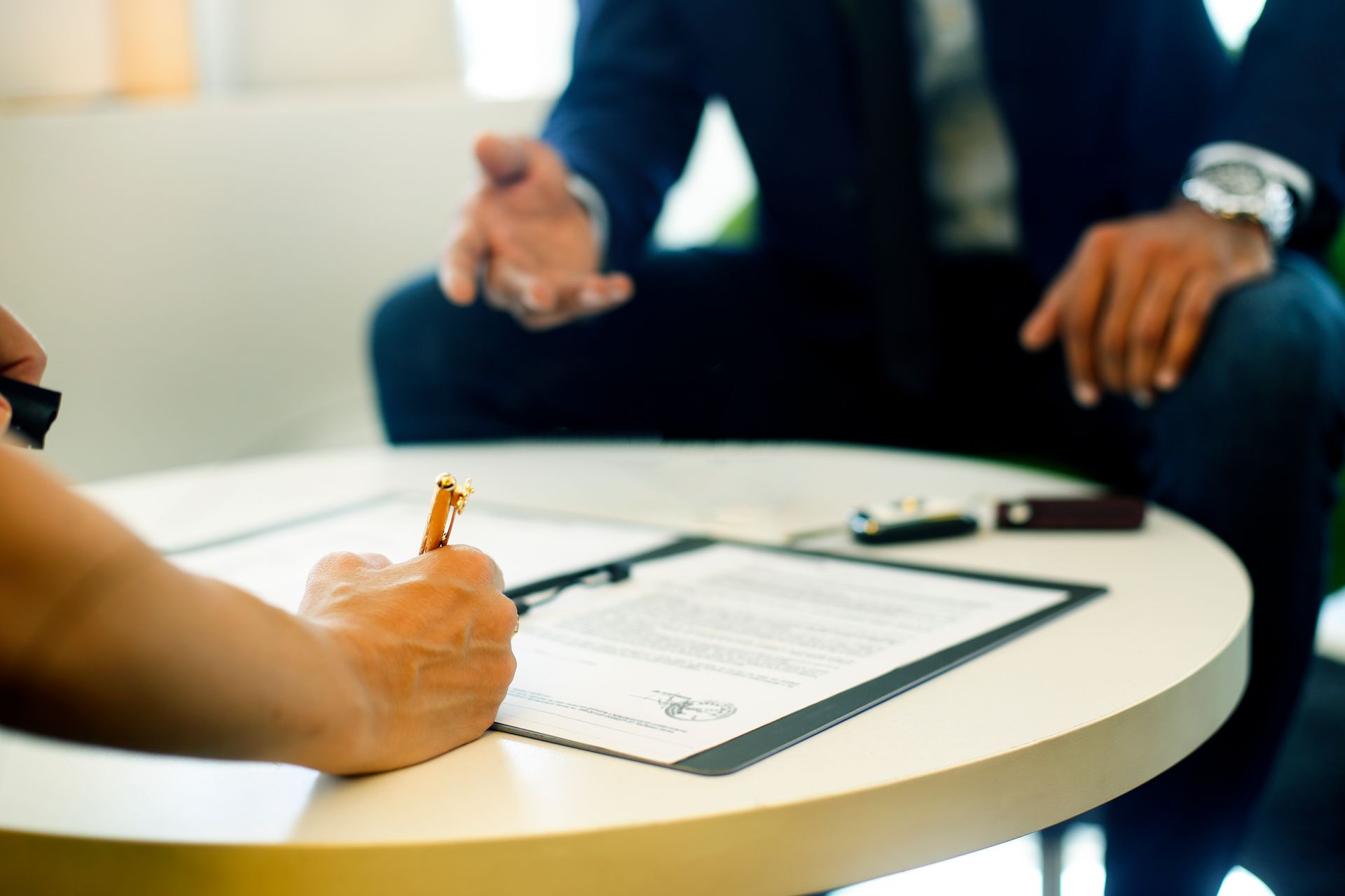 A man is sitting at a table signing a document. A man is sitting at a table signing a document.