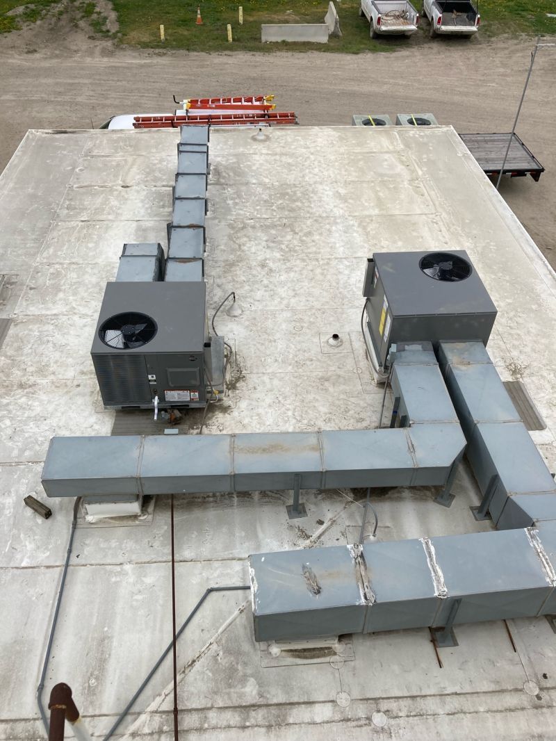 Rooftop HVAC ductwork and ventilation units on a flat gravel roof, viewed from above