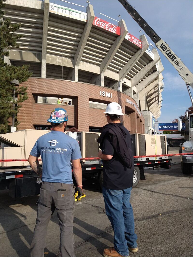 Two workers in hard hats watching a truck at a stadium construction site