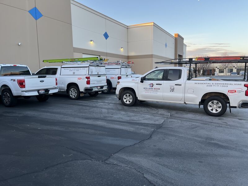 White utility trucks parked outside a beige warehouse at dusk