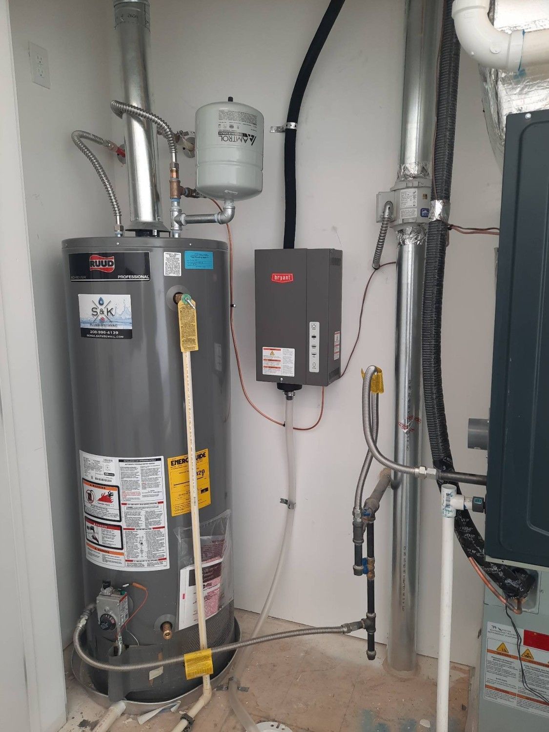 Water heater and utility equipment in a basement with pipes and electrical controls.