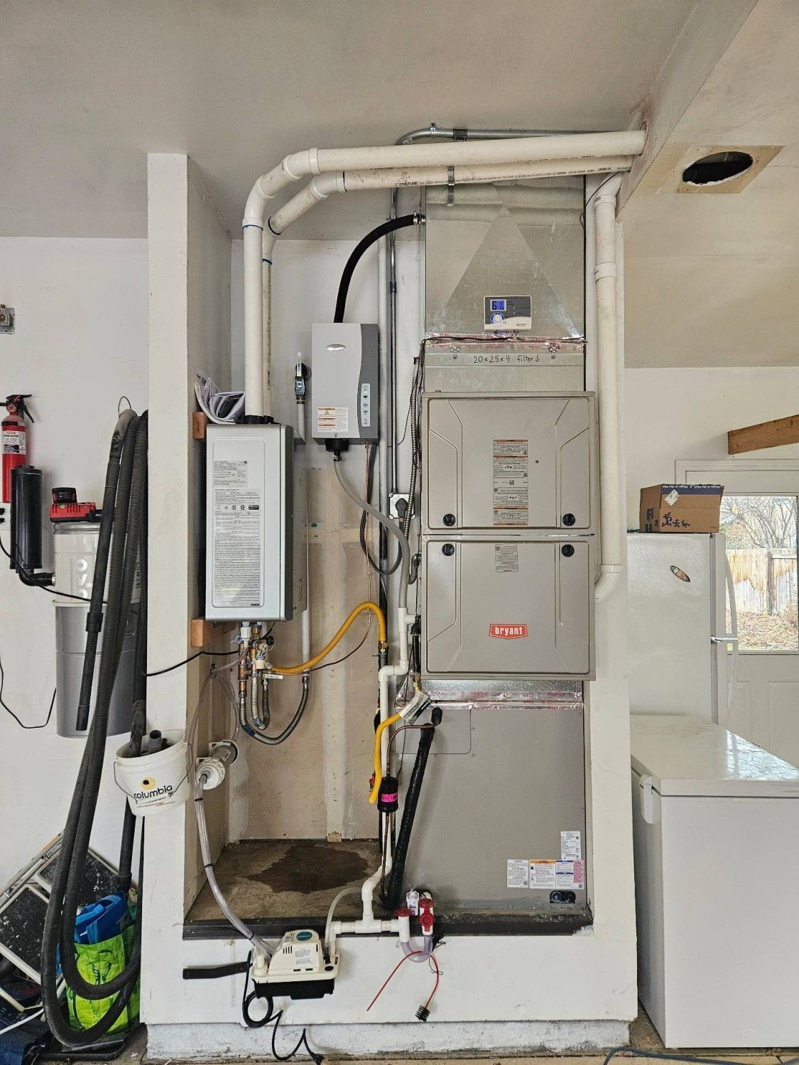 Gas furnace and HVAC equipment in a utility closet with exposed pipes, ducts, and wiring.