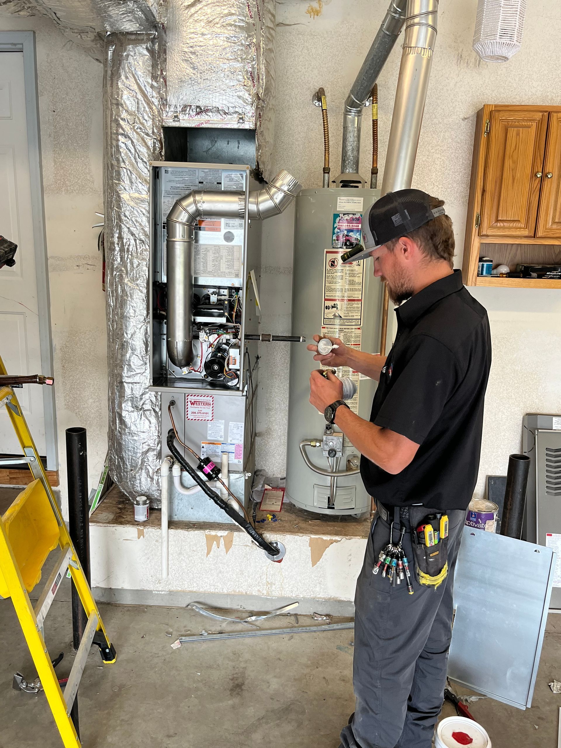 Technician inspecting an electrical panel in a utility room with ladders and tools nearby