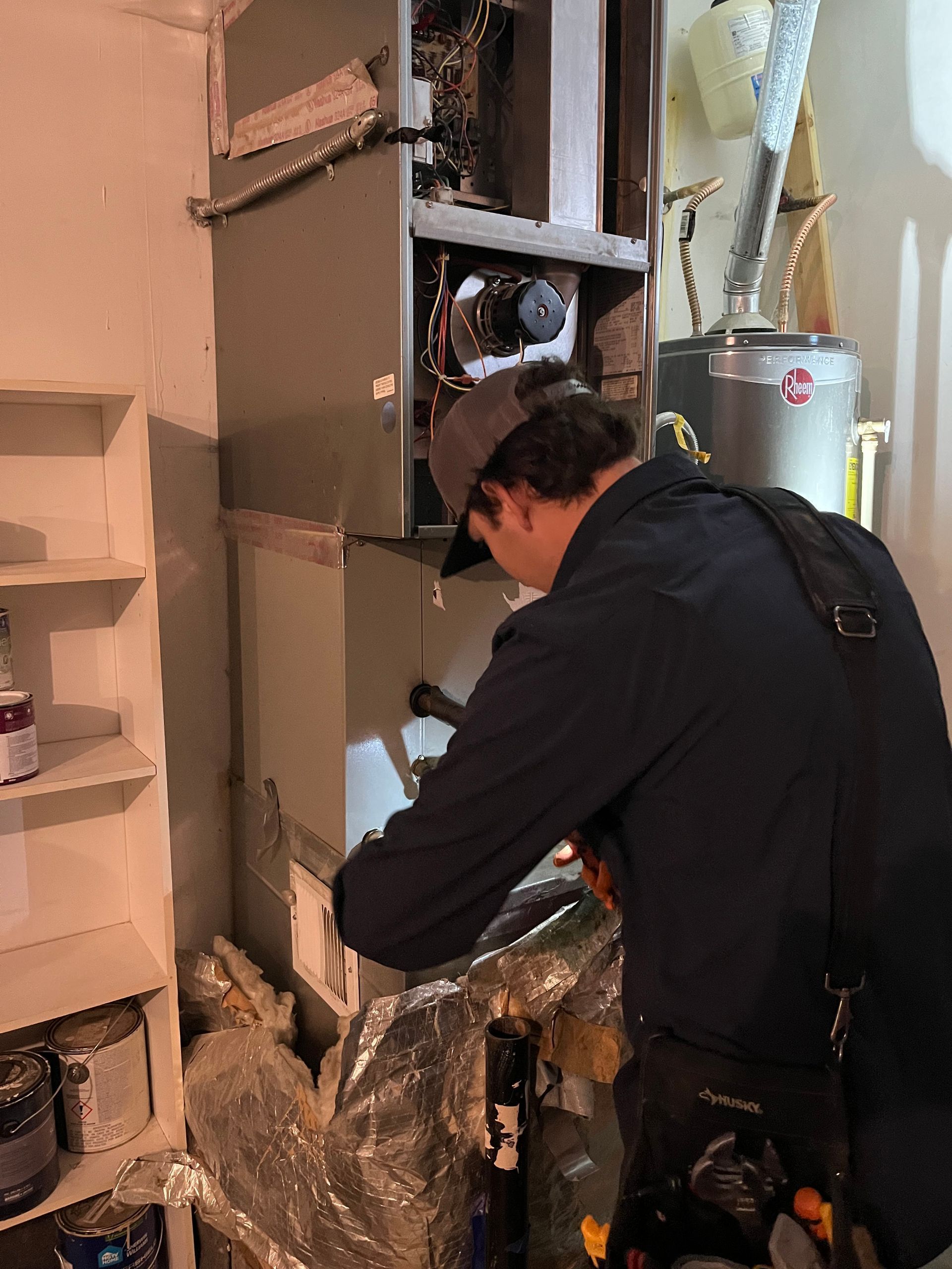Technician working on a large furnace or HVAC unit in a utility room