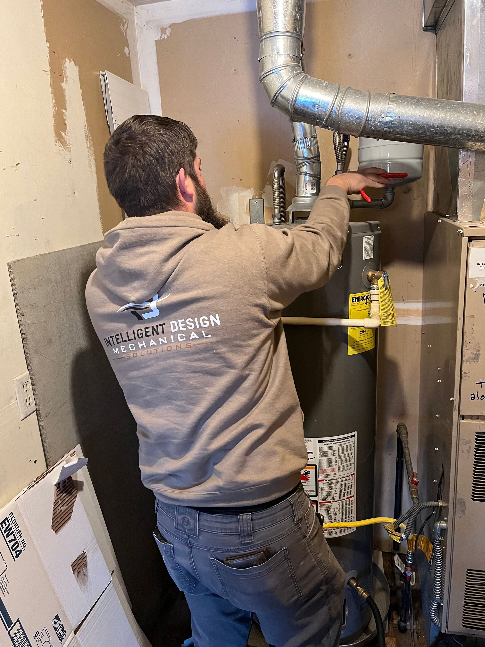Technician working on HVAC unit in a utility room, tightening a fitting near metal ductwork.
