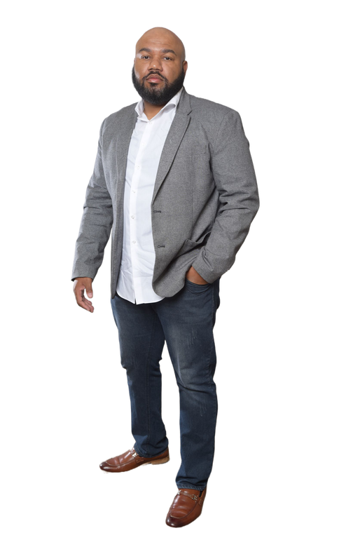 A man with a beard is standing with his hands in his pockets.