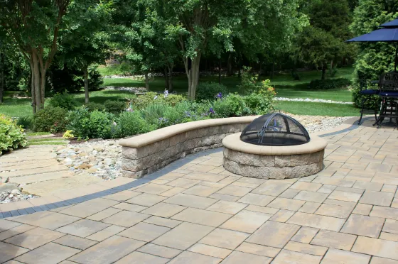 Stone patio with a curved bench and fire pit in a green garden courtyard