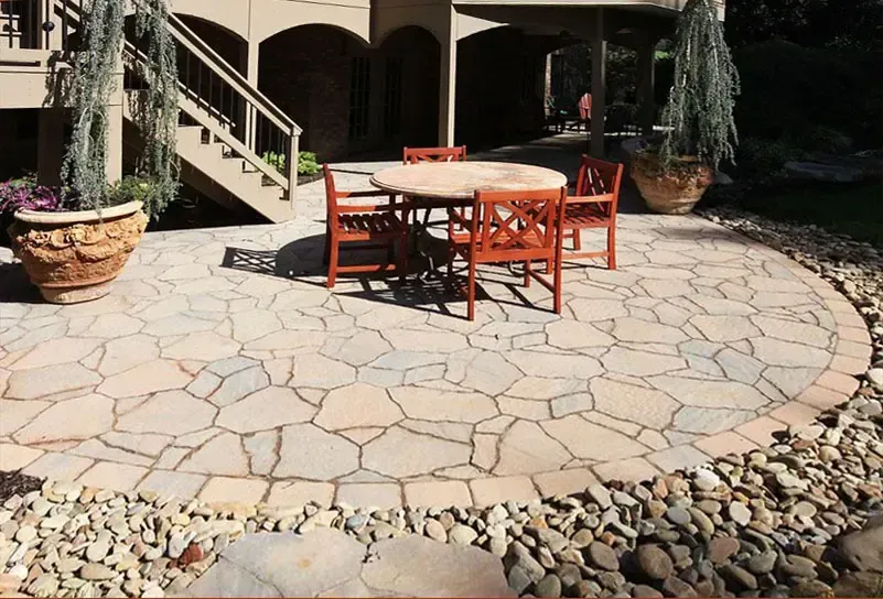 Stone patio with a red wooden table and chairs in front of a house entrance