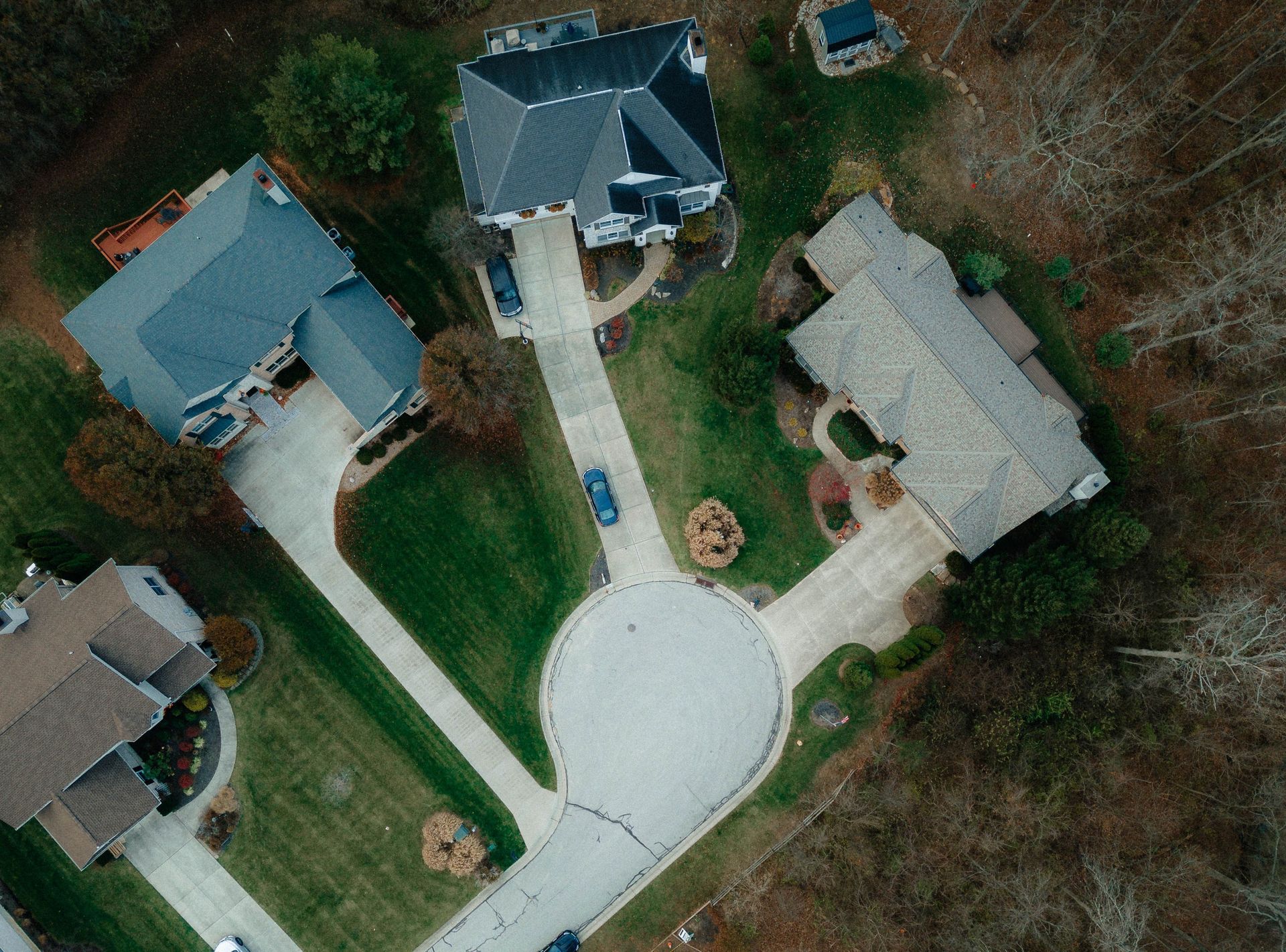 Aerial view of a cul-de-sac with several houses, driveways, and trees in a suburban neighborhood.