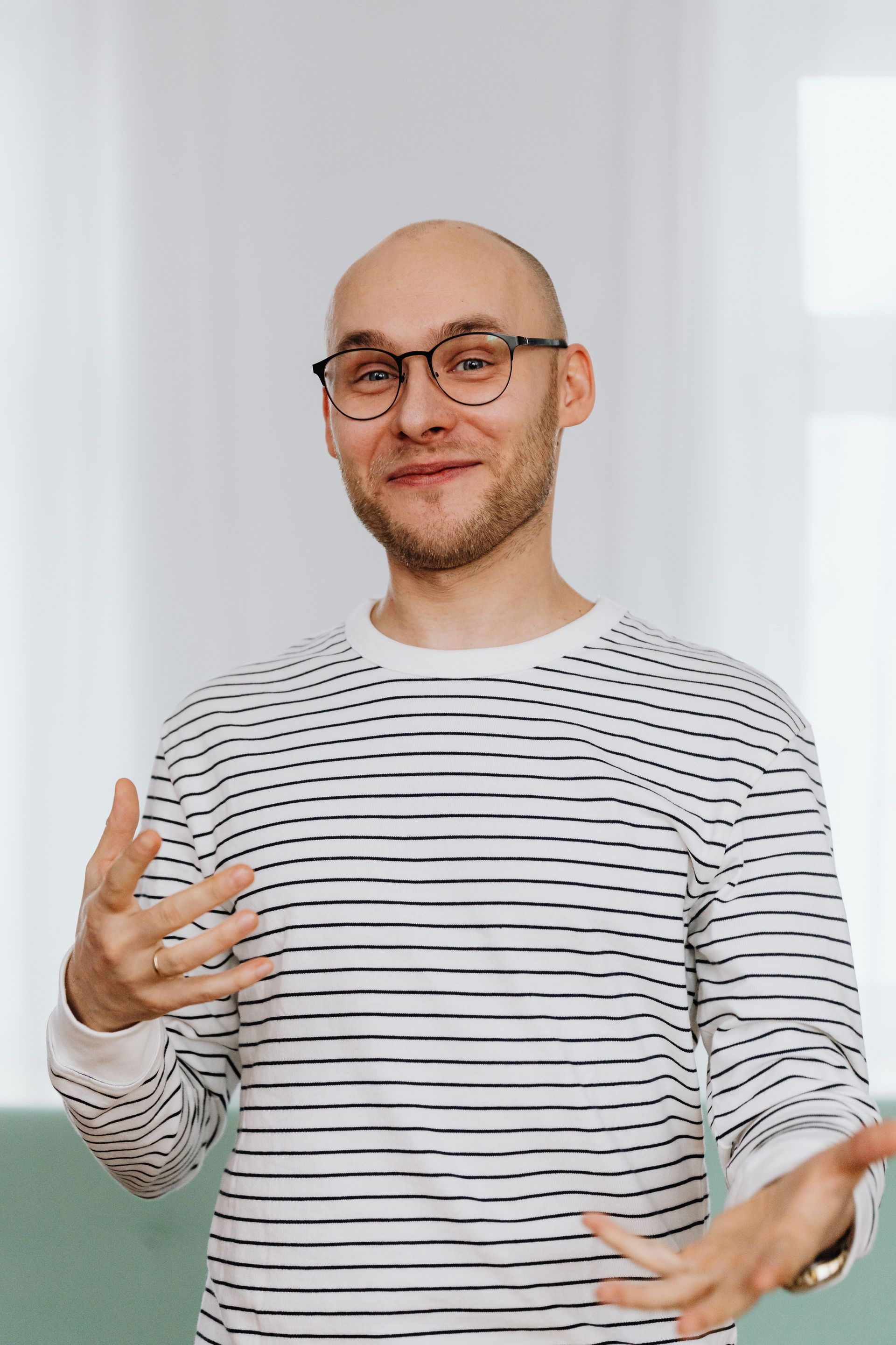 Person in striped shirt gesturing while speaking in a bright indoor setting