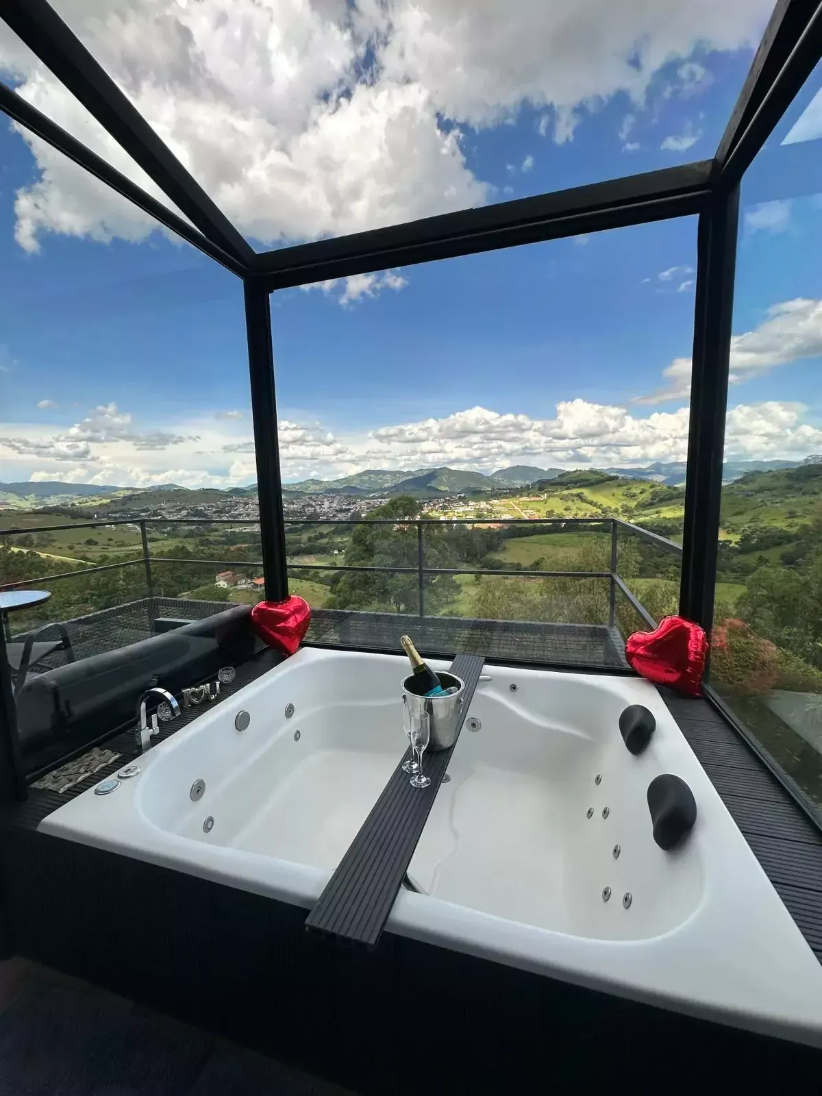 Uma banheira de hidromassagem com vista para um vale e montanhas. Chalé Pedra Negra