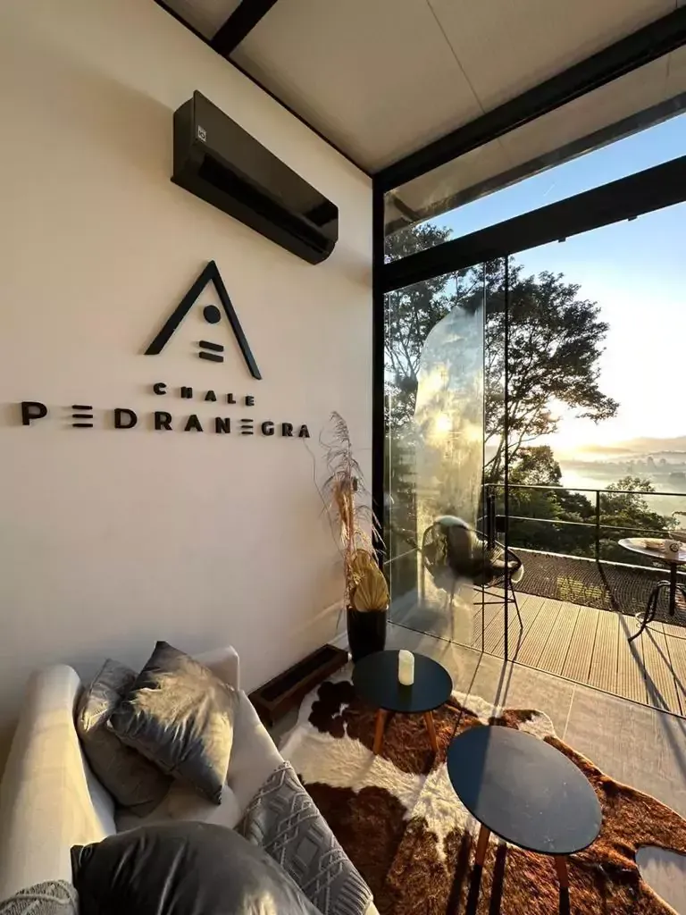 Uma sala de estar com um sofá e mesas e uma placa na parede que diz pedra negra. Chalé Pedra Negra