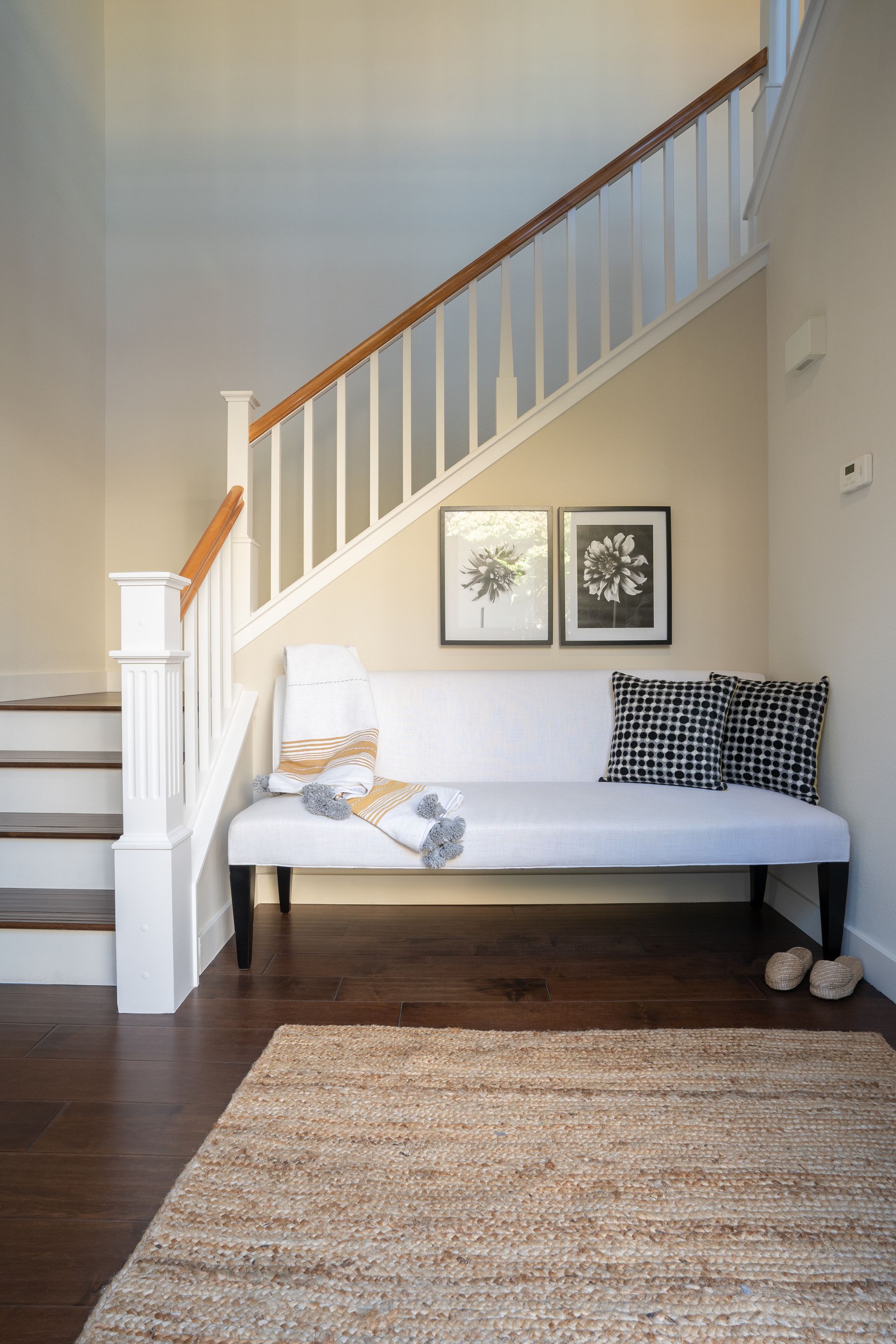 There is a bench under the stairs in the hallway.