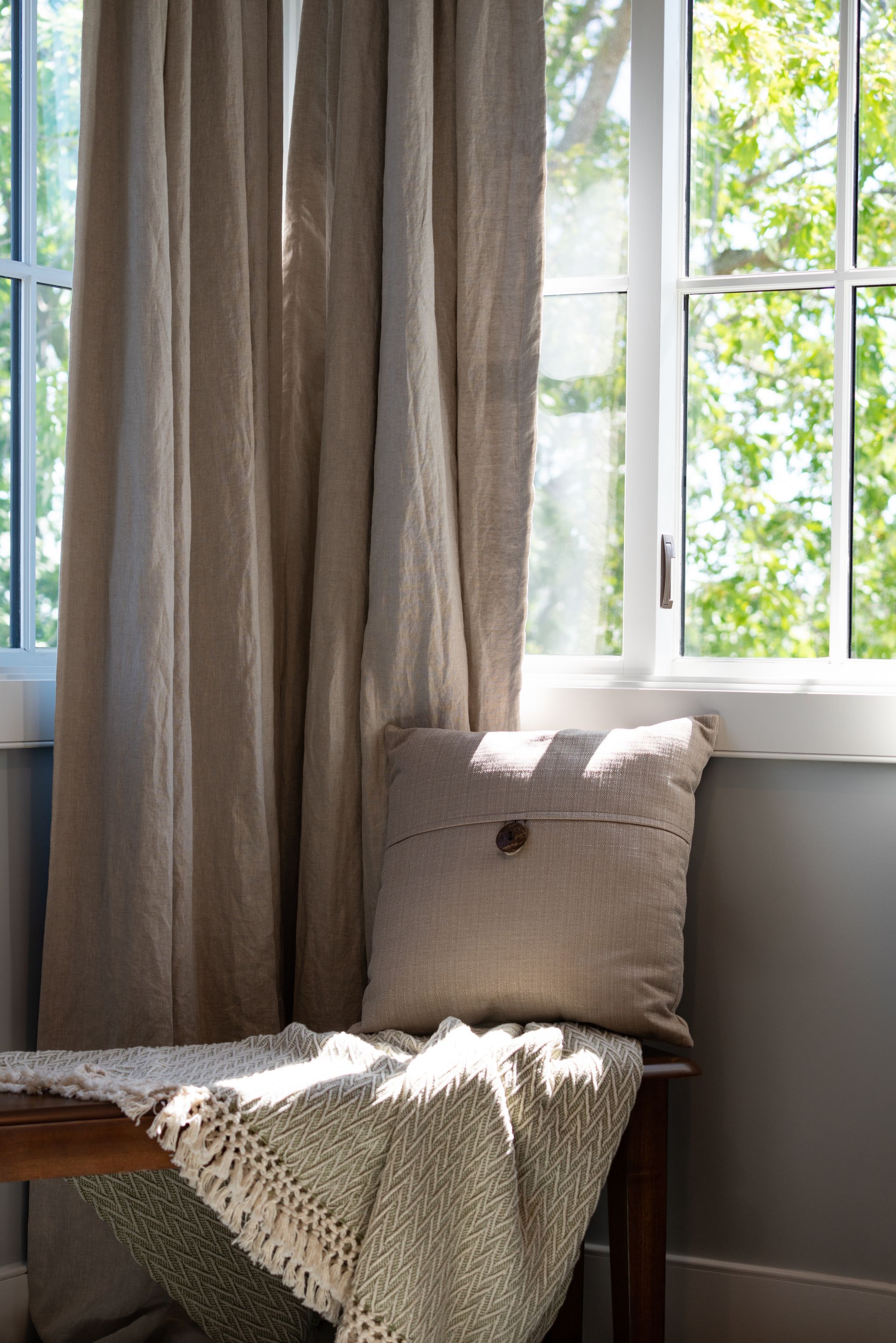 A pillow is sitting on a bench in front of a window.