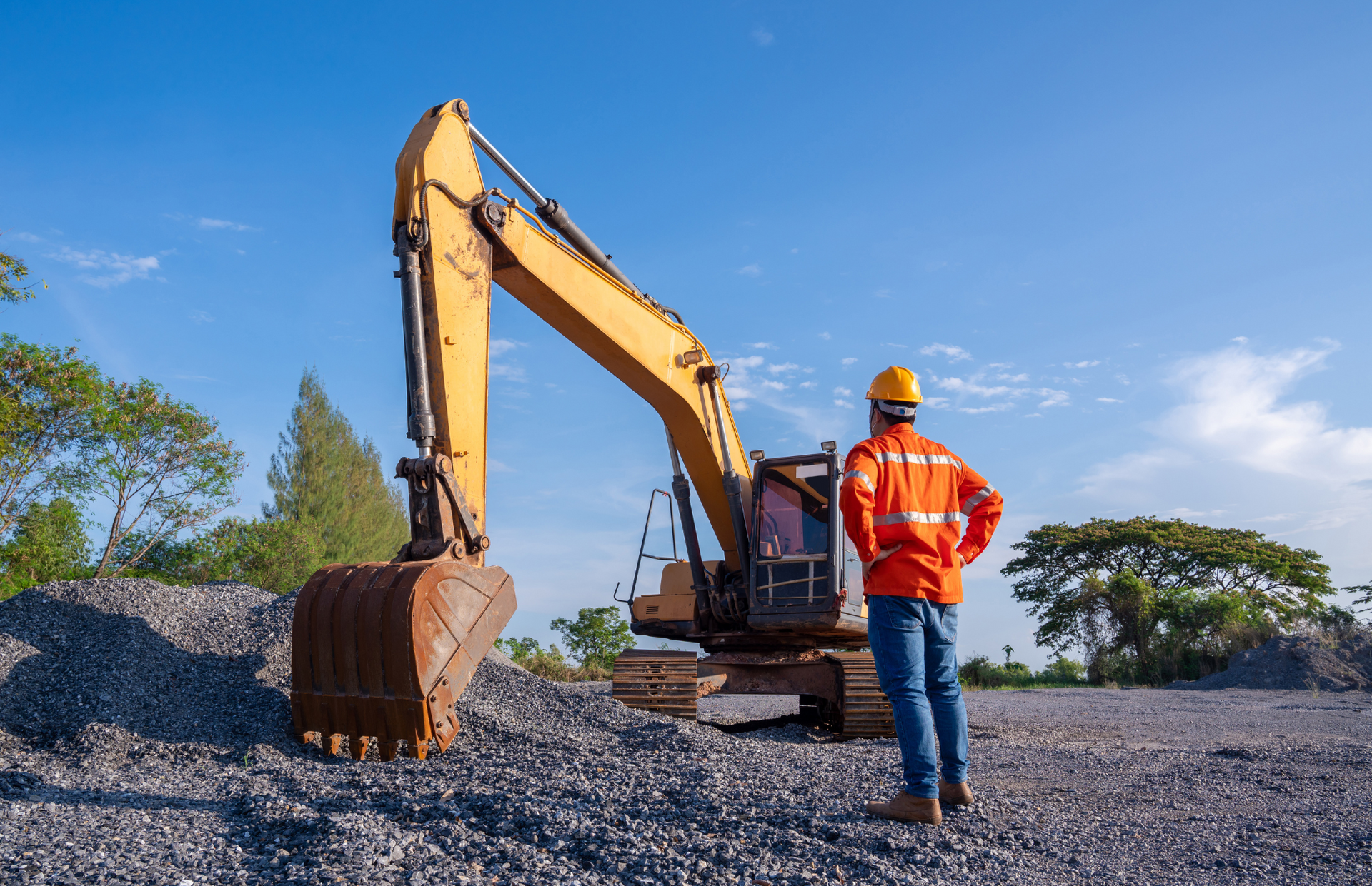 Excavator loading a dump truck with rocks in a quarry; orange machinery.