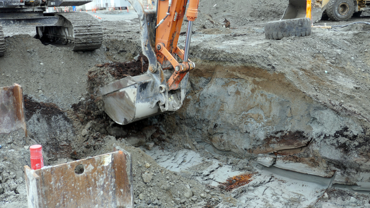 Orange excavator digging earth at construction site.