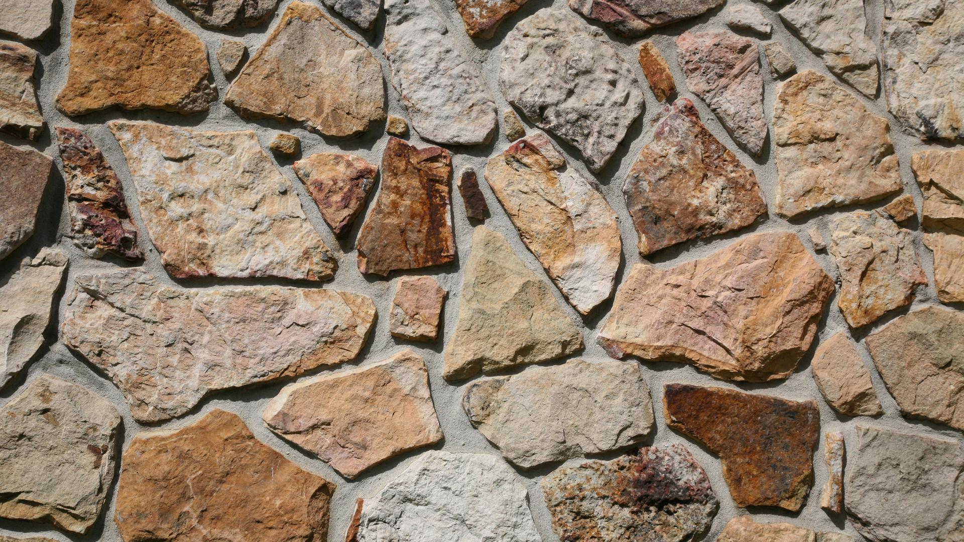 Stone wall with rough, irregular stones in shades of brown and beige.