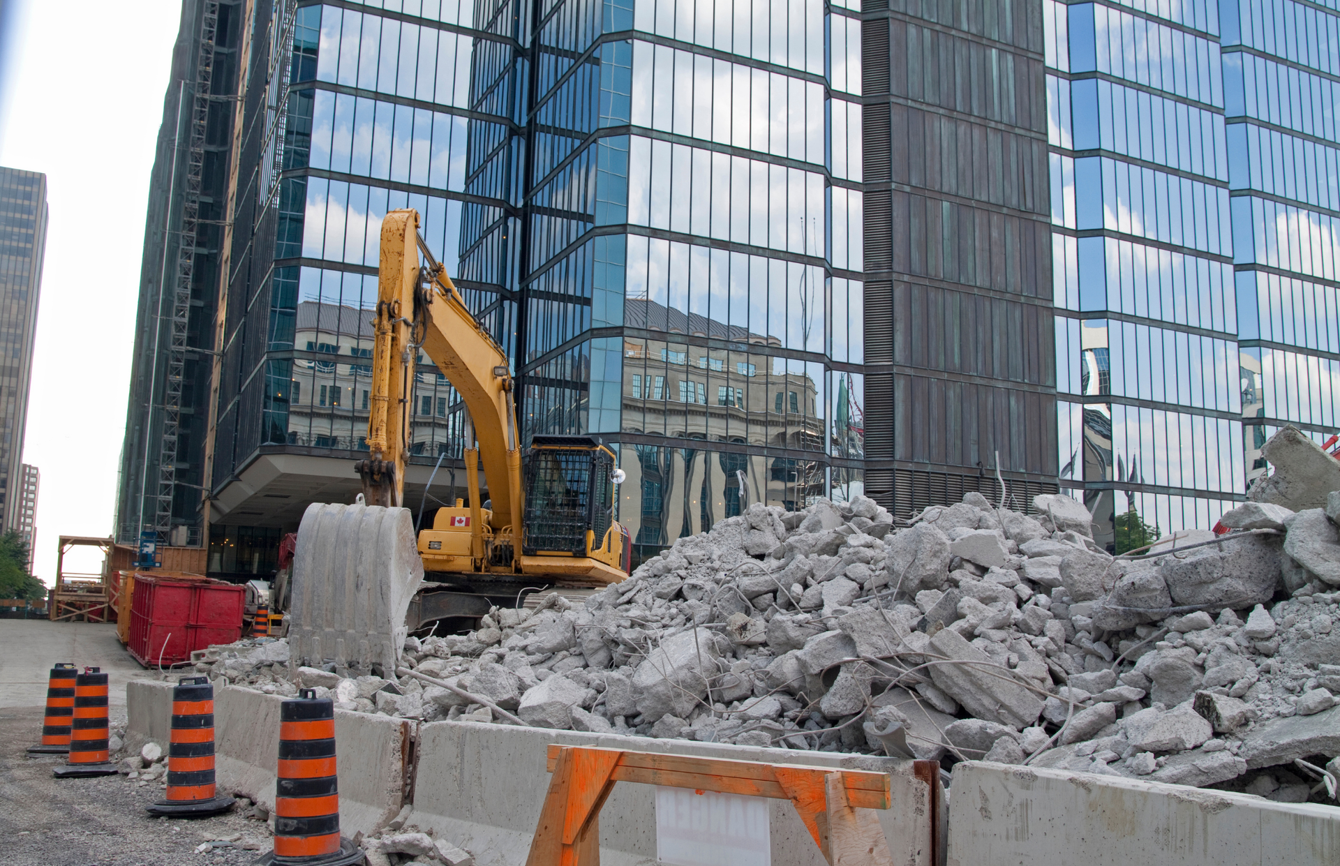 Yellow backhoe on a dirt pile at a construction site.