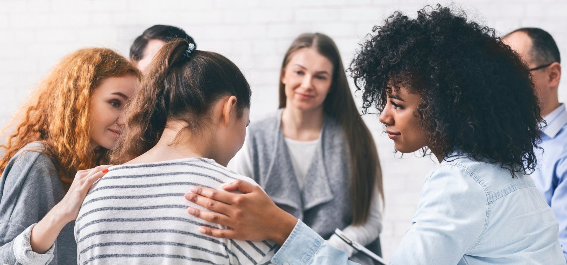A group of people sitting in a circle, one person is being comforted.