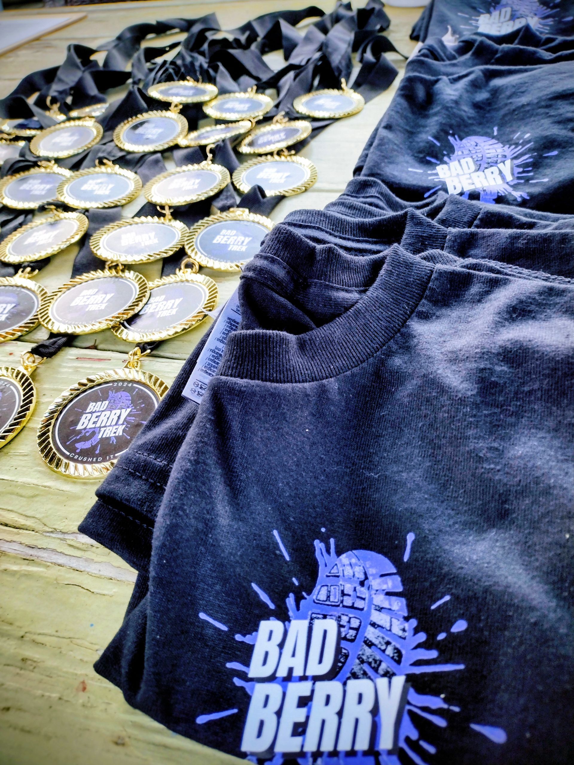 Black t-shirts and gold medals with black ribbons, ready for an event, displaying the