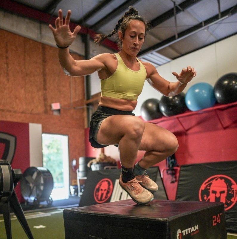 A woman is squatting on a titan box in a gym