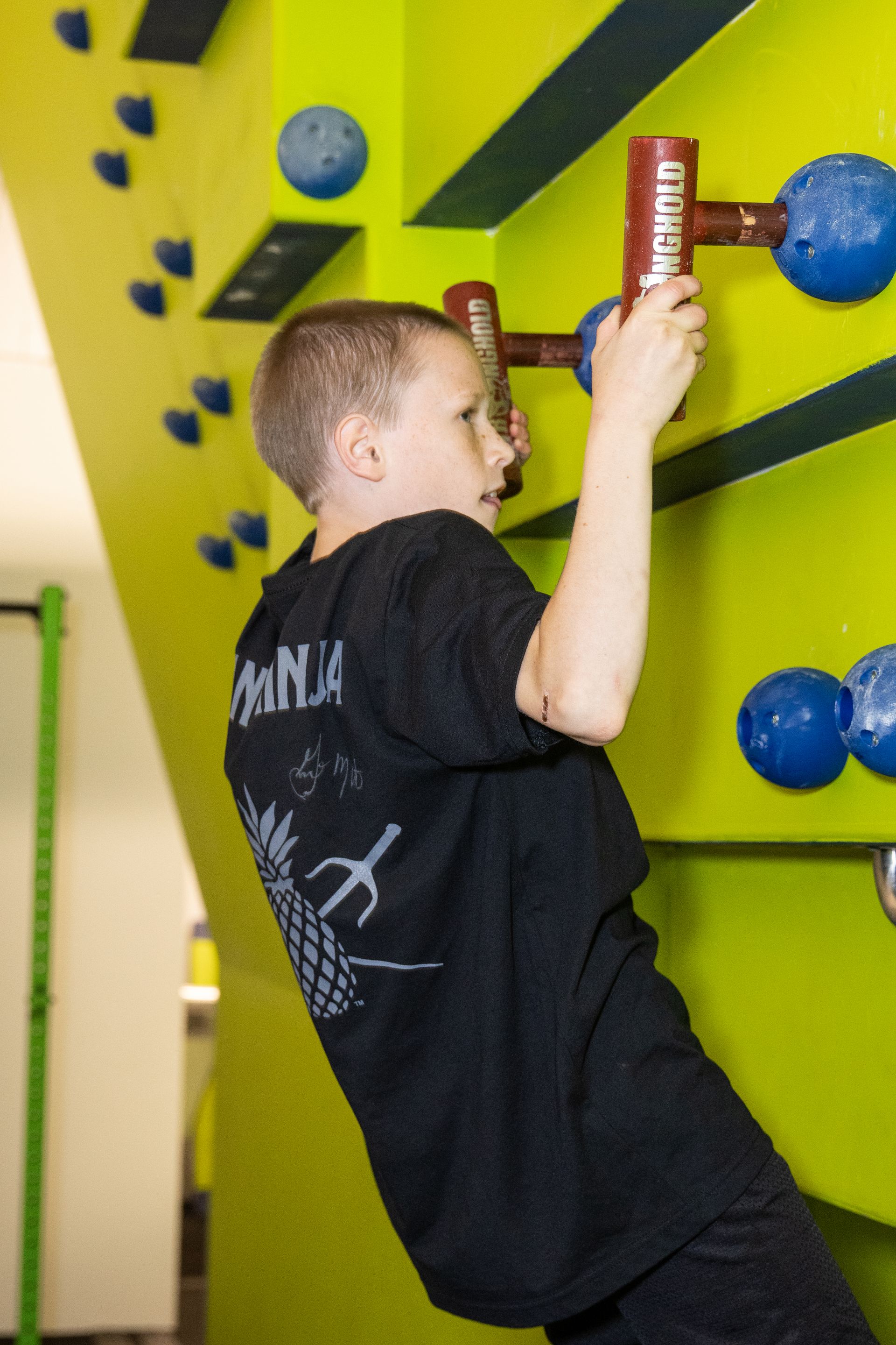 A young boy wearing a black shirt with the word ninja on it
