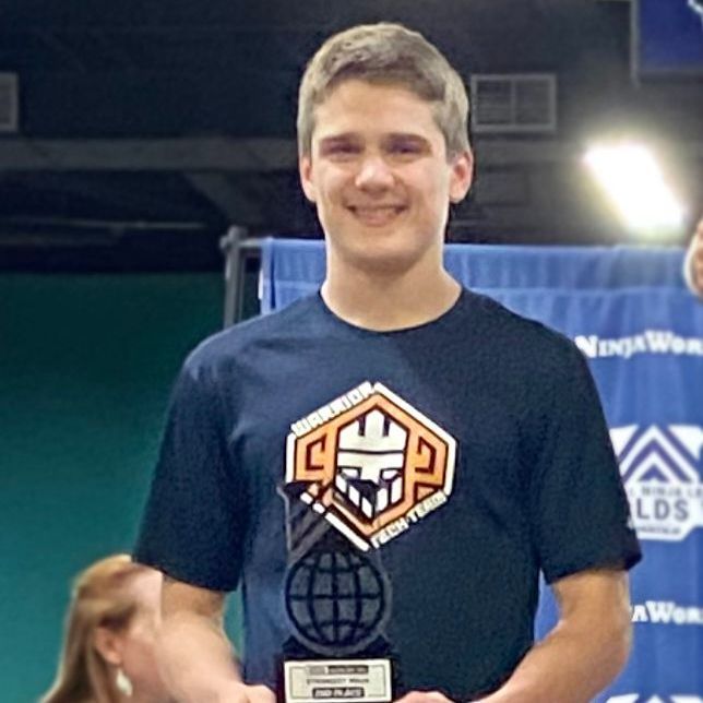 A young man in a blue shirt is holding a trophy